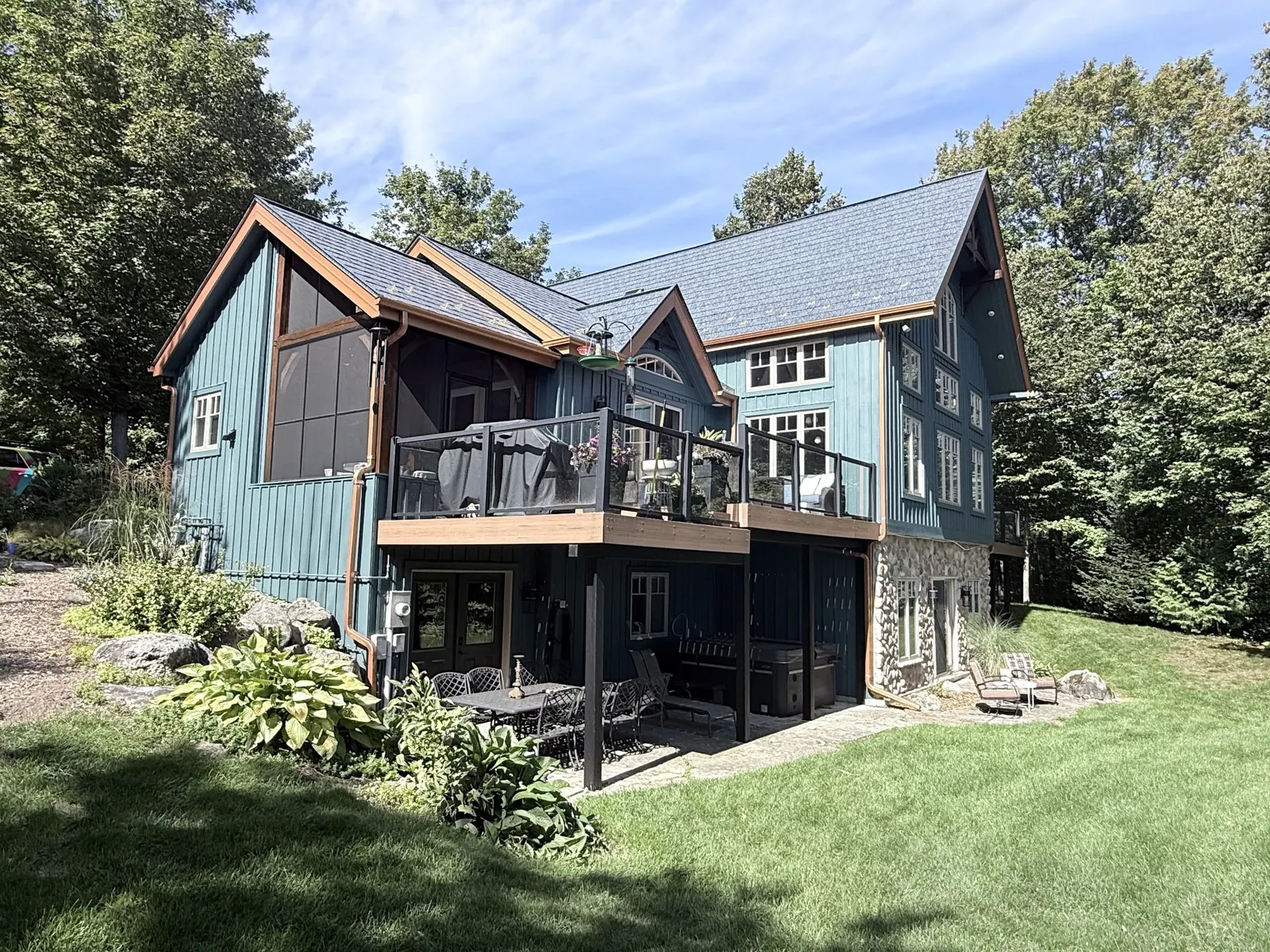 Blue-painted house with a deck and a stone base